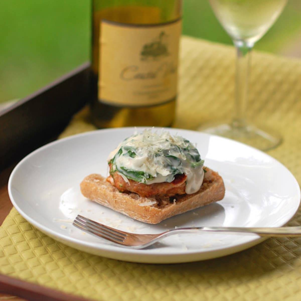 Garlic Parmesan Burger with Creamed Spinach Sauce on a plate with a fork.