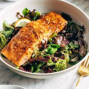 A piece of salmon sitting on a bed of greens.
