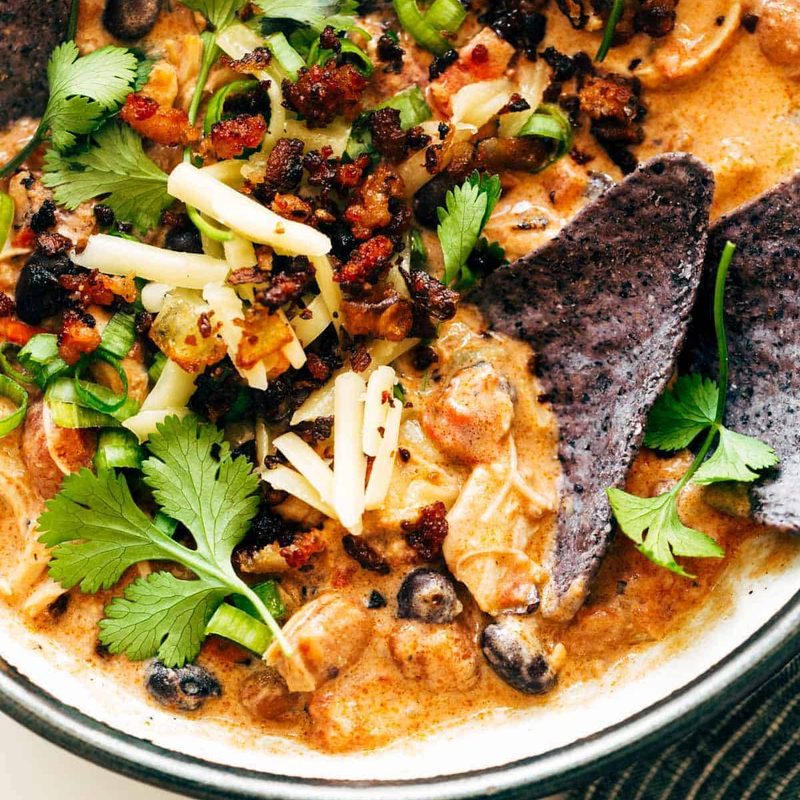 Chips in a bowls of chili and garnishments.