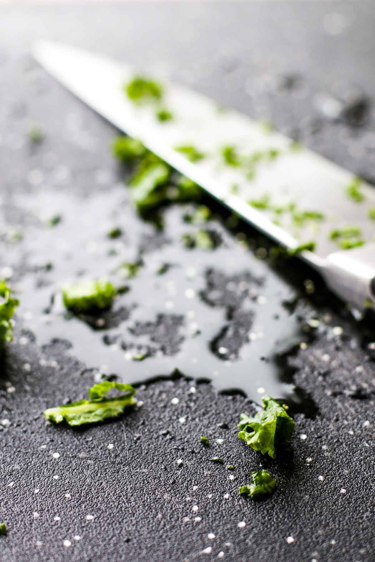 Herbs on a cutting board with a knife.