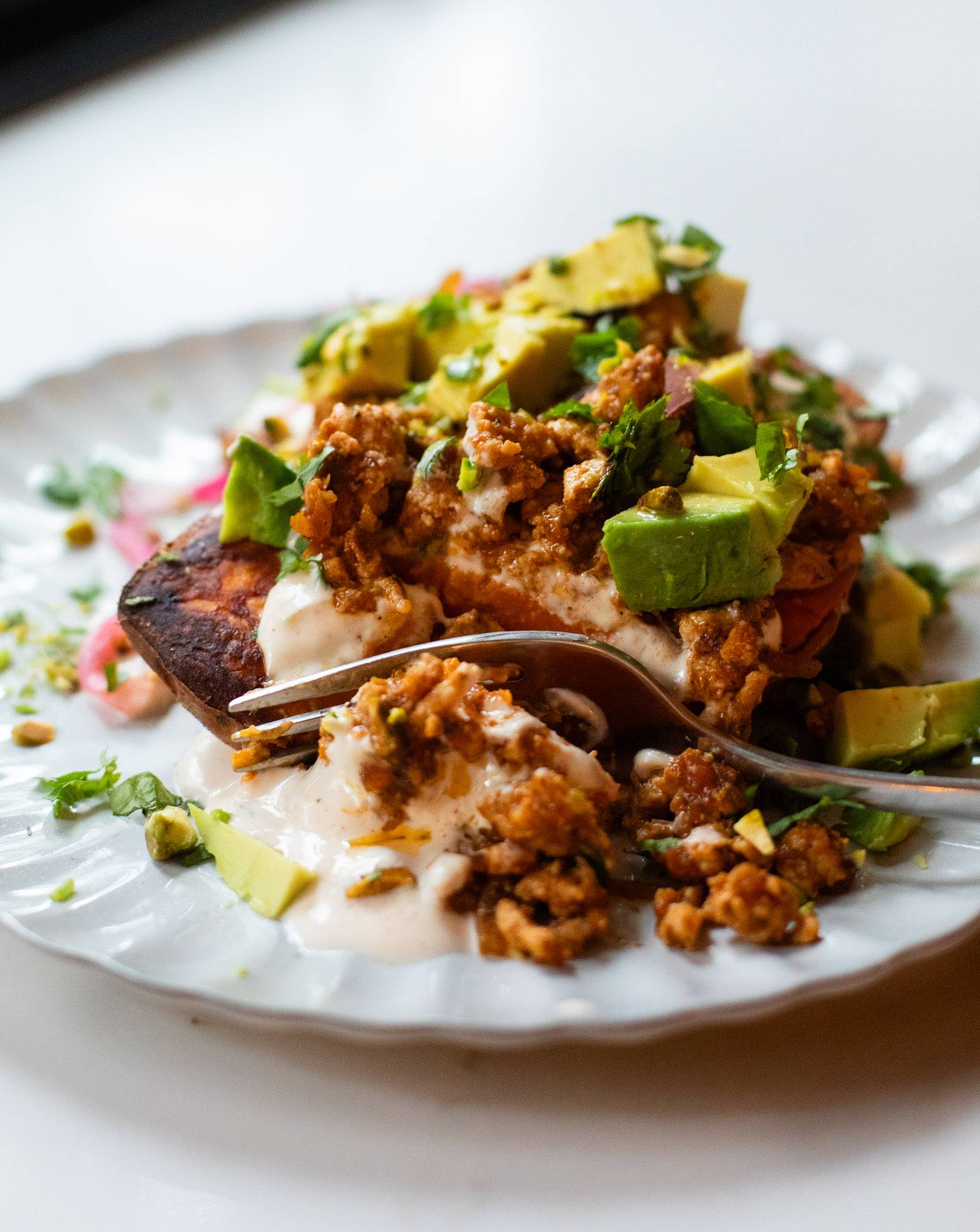 Roasted sweet potatoes on a plate with ground turkey and avocado and chipotle sauce.