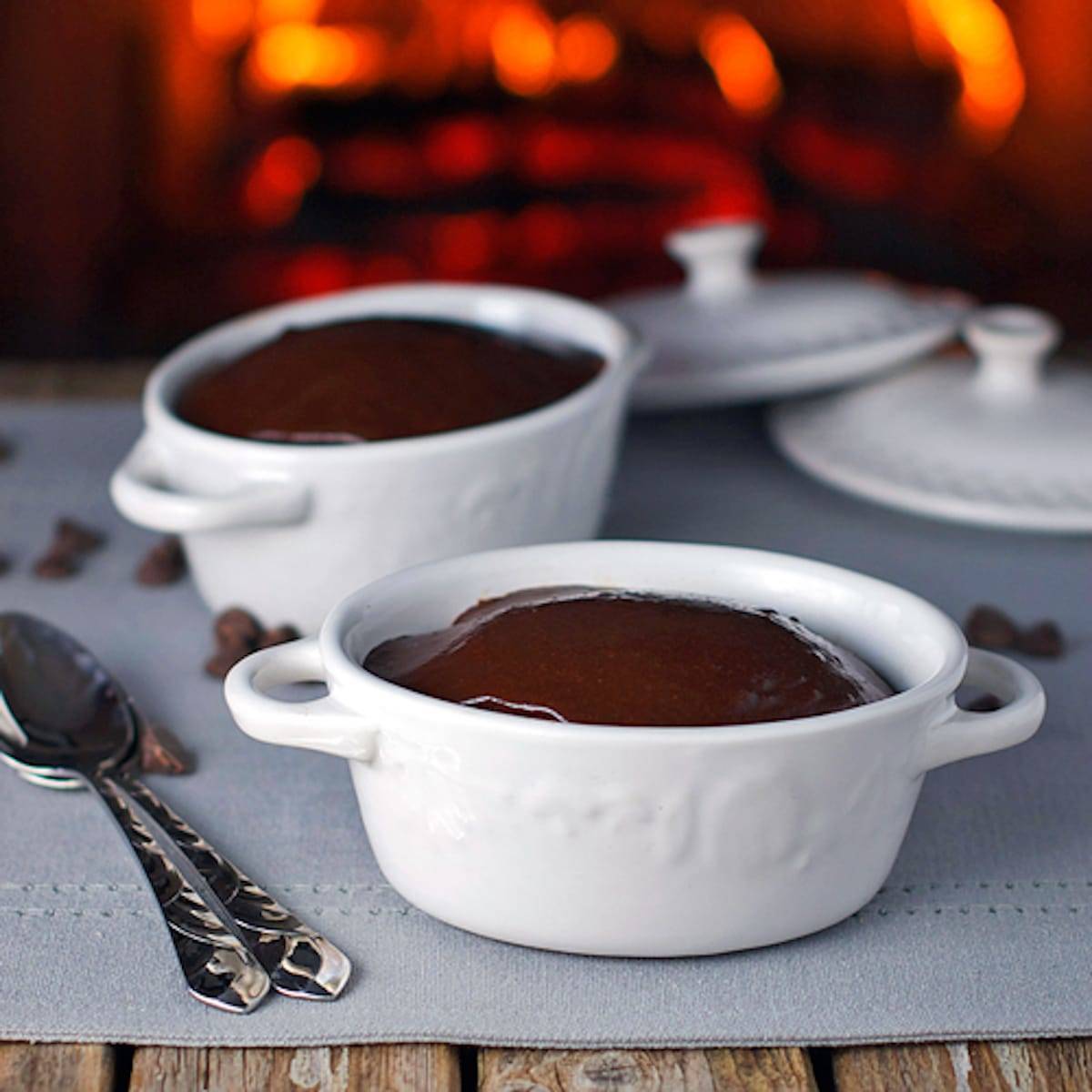 Chocolate cherry fudge cake topped with homemade fudge frosting in two white dishes with spoons.